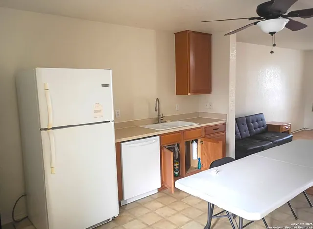 a kitchen with stainless steel appliances granite countertop a refrigerator a stove a sink and white countertops with wooden floor