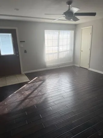 an empty room with wooden floor and windows