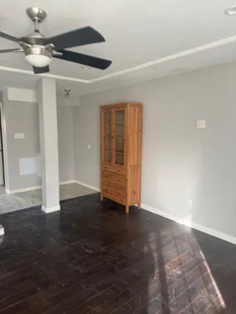 a view of an empty room with wooden floor and a ceiling fan