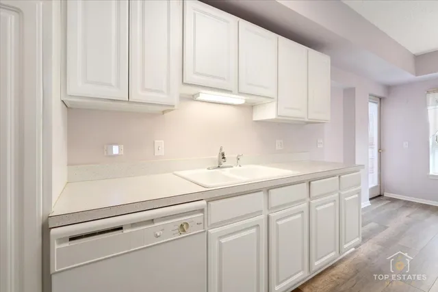 a kitchen with white cabinets and sink