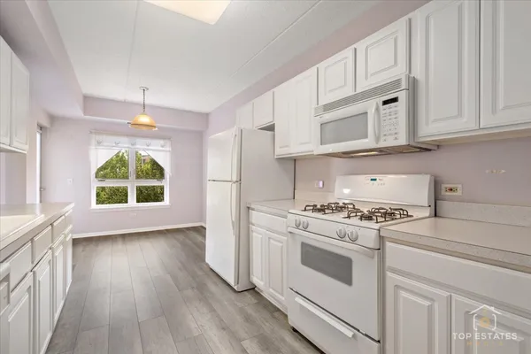 a kitchen with wooden floors and white cabinets
