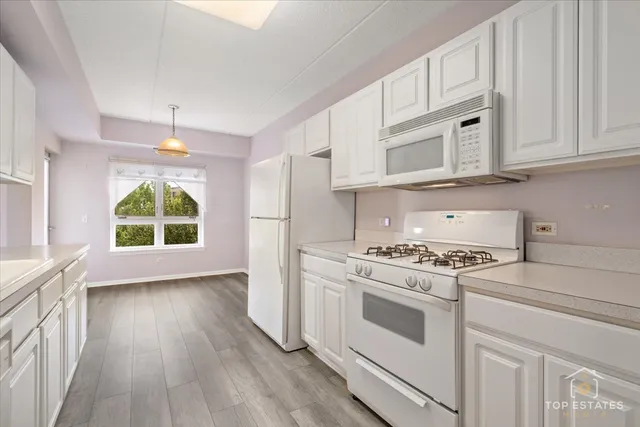 a kitchen with wooden floors and white cabinets