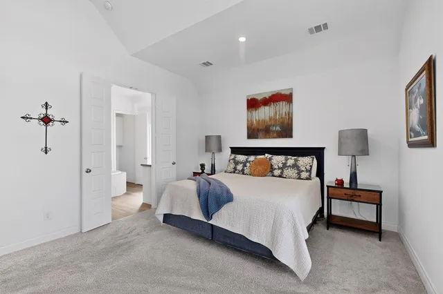 a spacious bedroom with a bed and a lamp