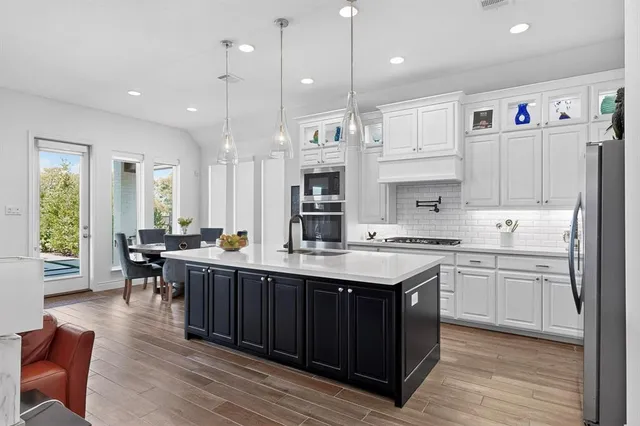 a kitchen with stainless steel appliances granite countertop a stove a sink dishwasher and a refrigerator with wooden floor