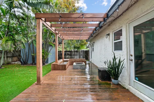 a view of a patio with table and chairs potted plants and floor to ceiling window