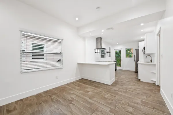 a large white kitchen with kitchen island a stove a sink dishwasher and a refrigerator with wooden floor