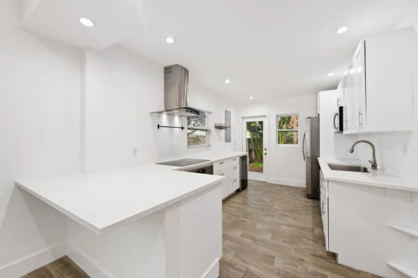 a large white kitchen with sink a refrigerator and cabinets