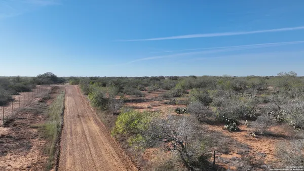 a view of a dry yard with wooden fence
