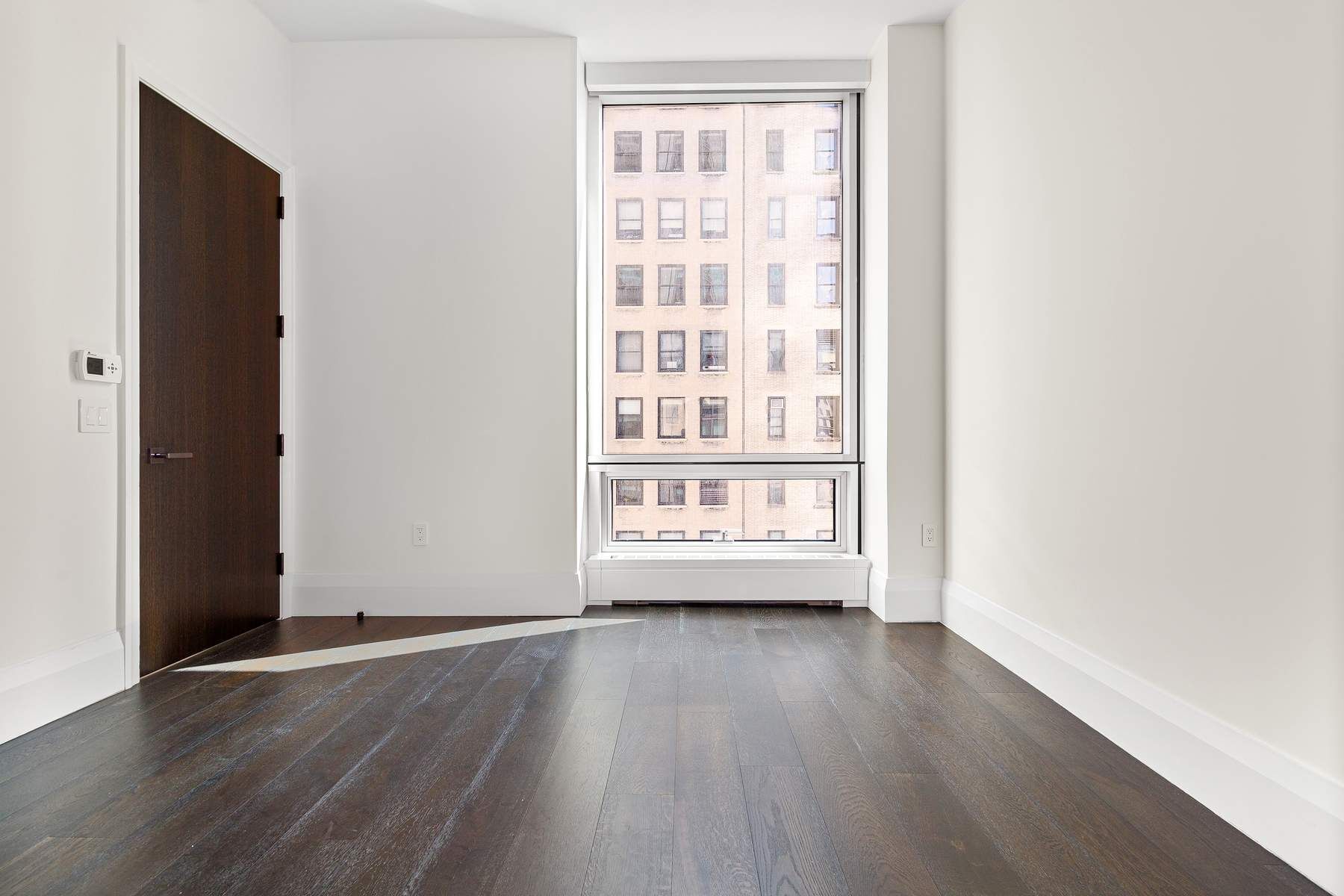 172 Madison Avenue, Unit 8B Manhattan, NY 10016 - Photo 6 of 11 an empty room with wooden floor and windows