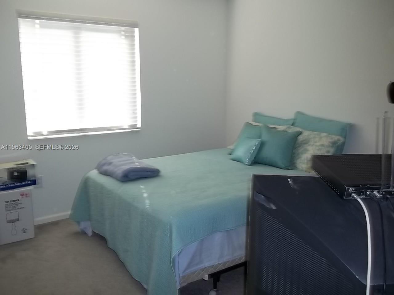 14057 Southwest 121st Place, Unit 724 Miami, FL 33186 - Photo 8 of 9 a bed sitting in a bedroom next to a window