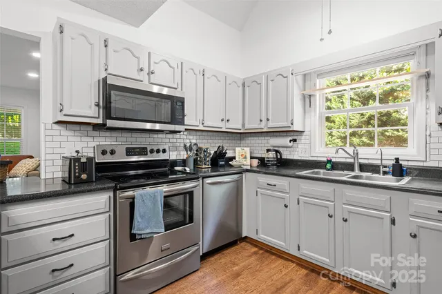 a kitchen with stainless steel appliances granite countertop a sink a refrigerator and window