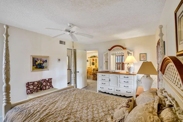 a bedroom with a bed large window and dresser