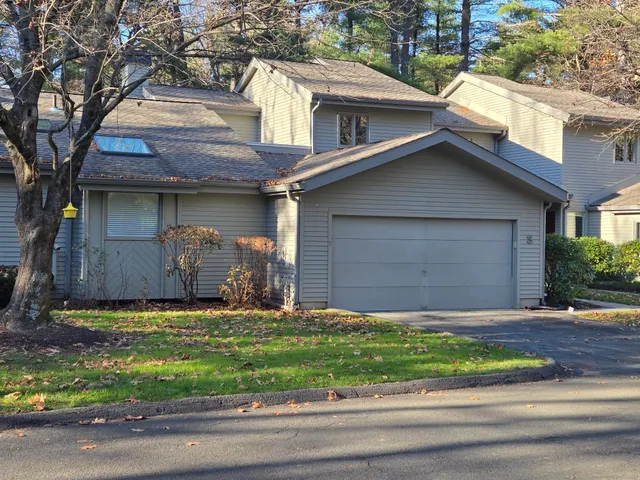 a view of a house with a yard plants and large tree