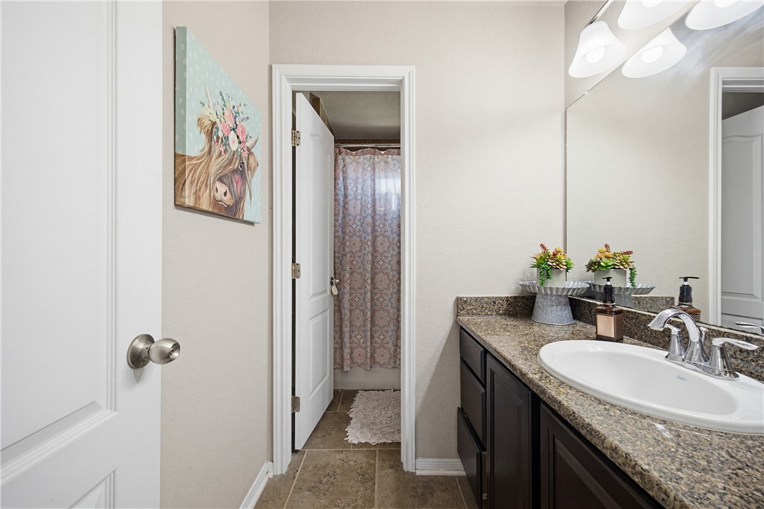 2129 Escondido Street Portland, TX 78374 - Photo 13 of 29 a bathroom with a granite countertop sink a mirror and a shower