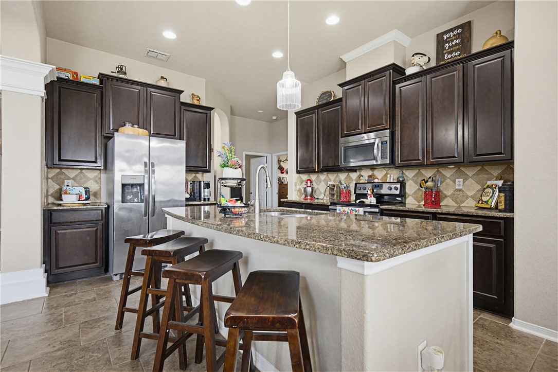 2129 Escondido Street Portland, TX 78374 - Photo 6 of 29 a kitchen with kitchen island granite countertop wooden cabinets and stainless steel appliances
