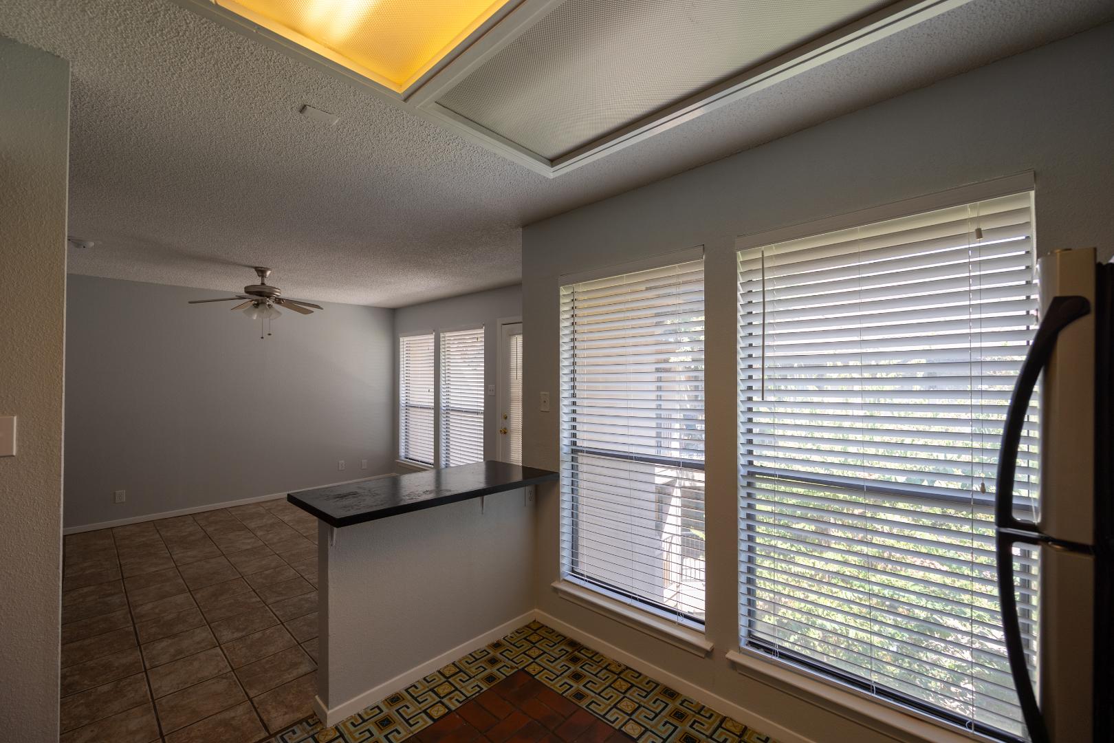 2110 Rio Grande Street, Unit 307 Austin, TX 78705 - Photo 6 of 12 A breakfast bar separates the tiled kitchen area from the living space, illuminated by ample windows and overhead lighting.