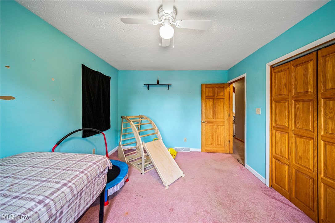 5050 Middle Road Conneaut, OH 44030 - Photo 29 of 35 Bedroom with carpet, a ceiling fan, a closet, and a textured ceiling