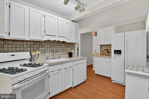 a kitchen with white cabinets and appliances