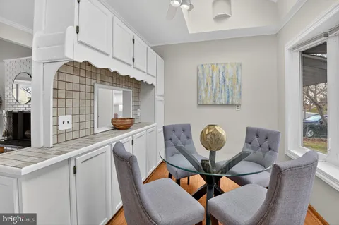 a kitchen with granite countertop a dining table chairs and white cabinets