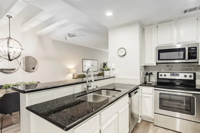 a kitchen with granite countertop a refrigerator and a stove top oven