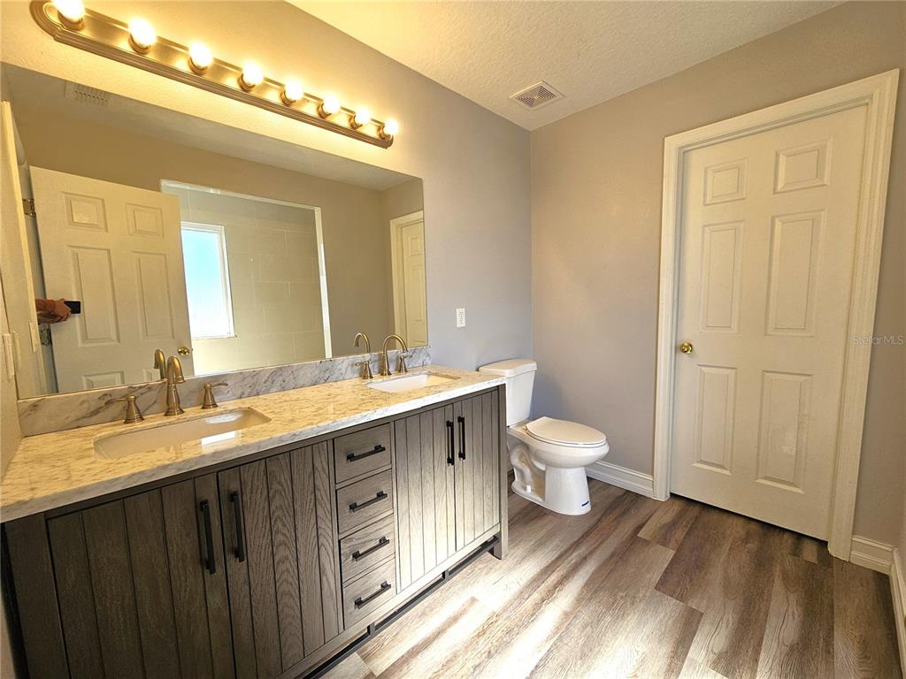 Undisclosed Address Orlando, FL 32818 - Photo 16 of 26 a bathroom with a granite countertop double vanity sink a mirror and a toilet