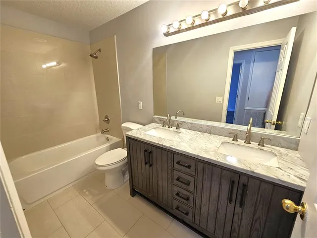 a bathroom with a granite countertop sink toilet mirror and bathtub