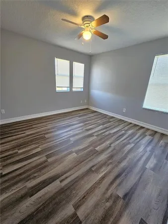 a view of an empty room with window and wooden floor
