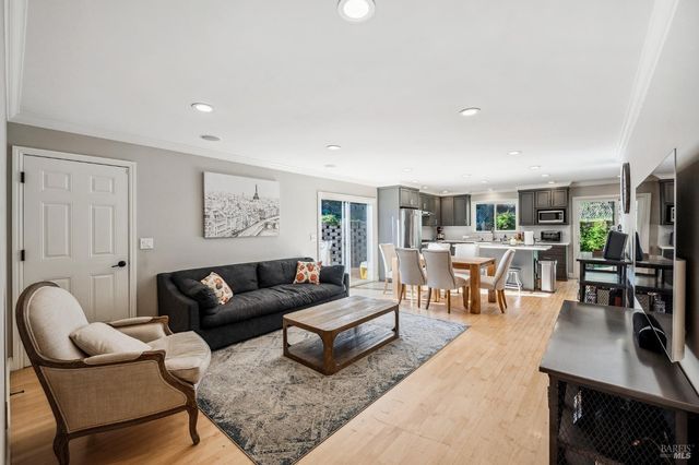 a living room with furniture potted plant and kitchen view