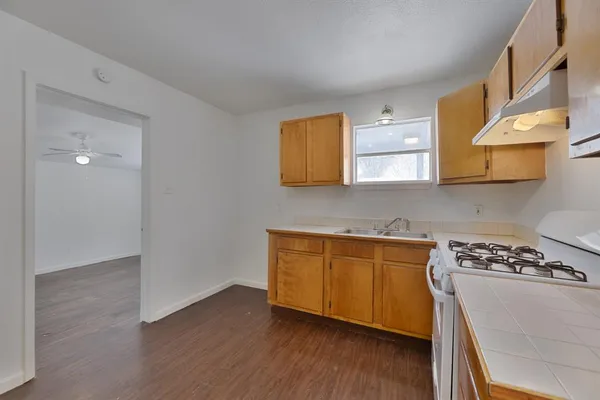a kitchen with stainless steel appliances granite countertop a stove a sink and a microwave with wooden floor