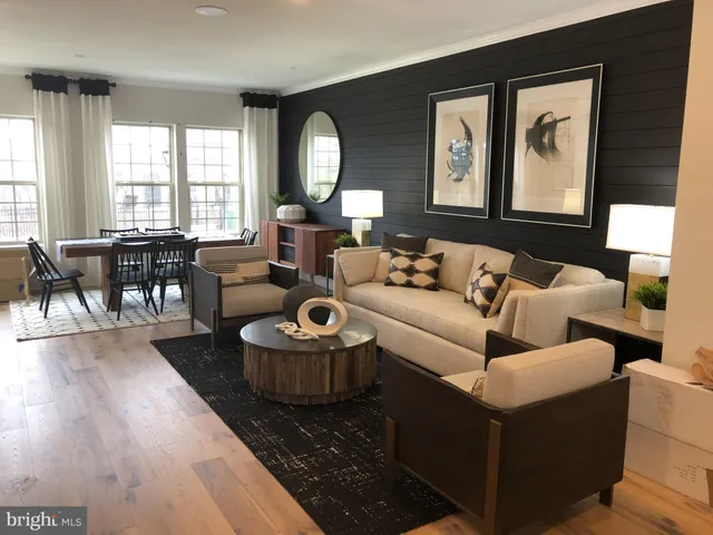 a living room with furniture and a large mirror next to a window