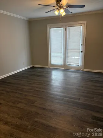 an empty room with wooden floor fan and windows
