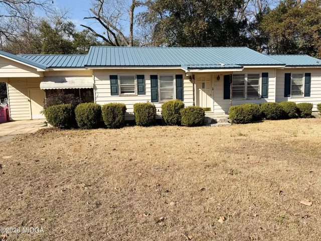 a front view of a house with a yard covered with trees