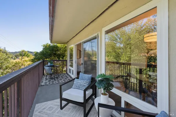 a balcony with wooden floor table and chairs