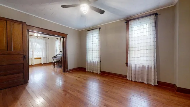 an empty room with wooden floor and windows
