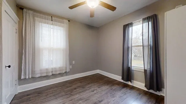 an empty room with wooden floor and a ceiling fan