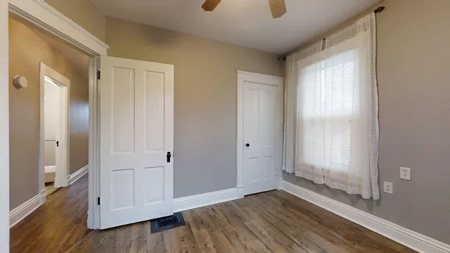 a view of an empty room with wooden floor and a window