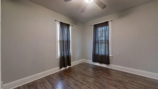 an empty room with wooden floor and a ceiling fan