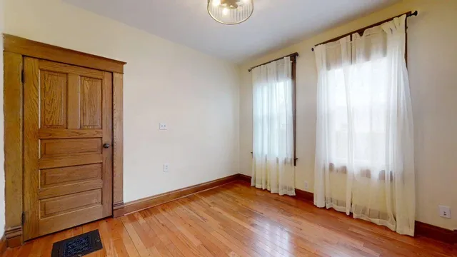 an empty room with wooden floor and window