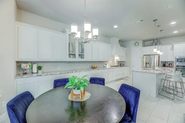 a kitchen with stainless steel appliances kitchen island granite countertop a dining table chairs and white cabinets