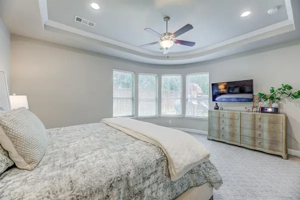 a spacious bedroom with a bed and flat screen tv