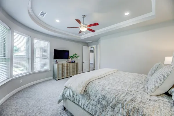 a spacious bedroom with a bed and a flat screen tv