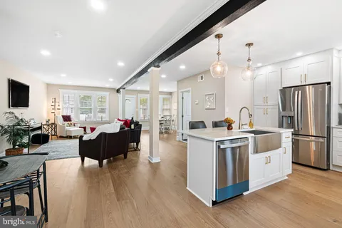 a kitchen with stainless steel appliances a stove top oven a refrigerator a dining table and chairs with wooden floor