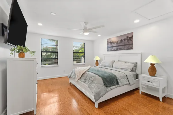 a bedroom with a bed a flat screen tv and windows