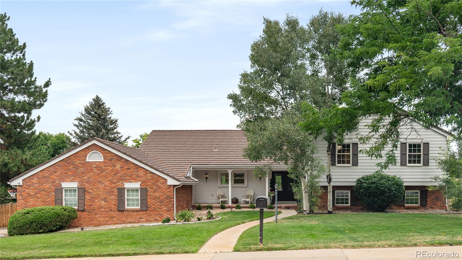a view of a yard in front of a house with plants and large tree