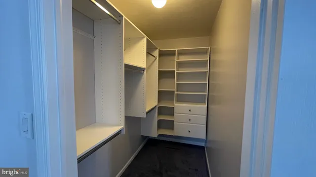 a view of walk in closet with empty racks