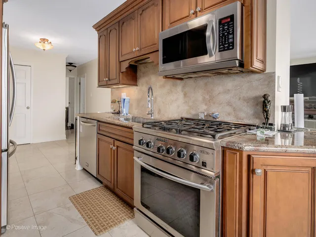 a kitchen with stainless steel appliances granite countertop a sink a stove and a refrigerator