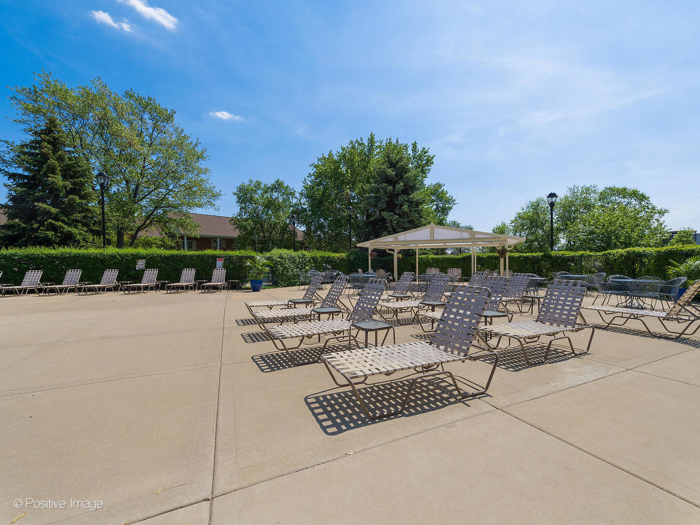 40 North Tower Road, Unit 12F Oak Brook, IL 60523 - Photo 24 of 25 a view of a patio with a table and chairs under an umbrella with large trees