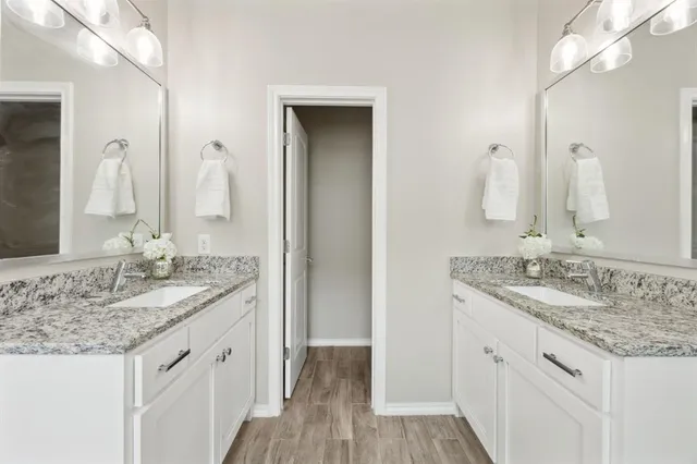 a bathroom with a granite countertop double vanity sink and mirror