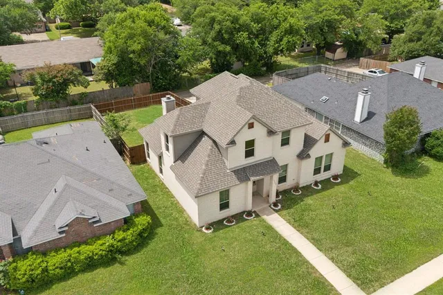 a aerial view of a white house sitting in big yard with large trees