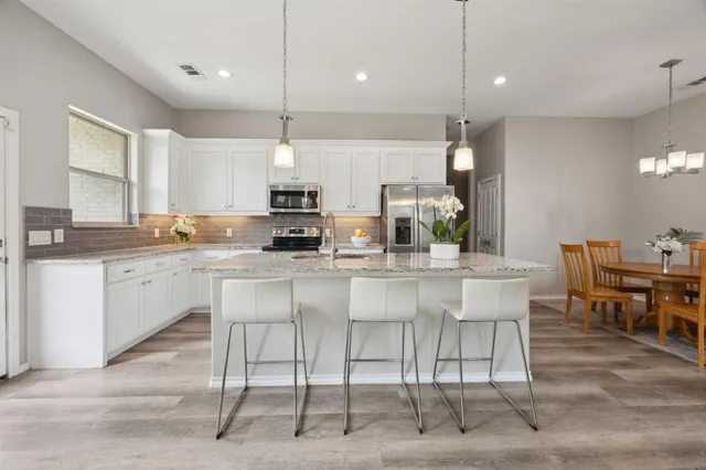a kitchen with kitchen island granite countertop a table chairs sink and cabinets